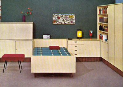 Chambre-bureau sur mur vert sombre, mobilier clair et lit escamotable — catalogue Musterring, Allemagne, 1960